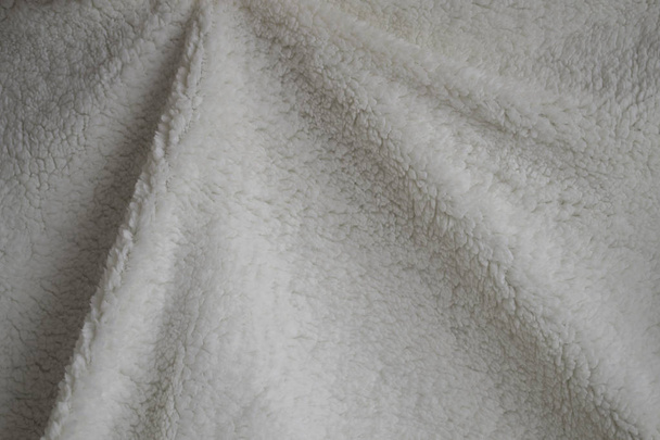 Textur eines weichen Karos. zerknitterte weiße warme Decke. Stoff zerknittert in Falten für Hintergrund oder Tapete. - Foto, Bild
