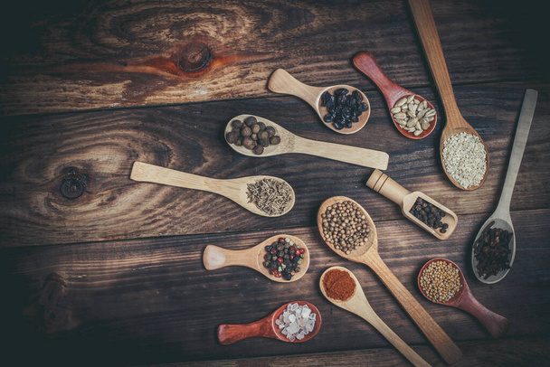 Different spices and ingredients in wooden spoons on a wooden table for cooking - Photo, image