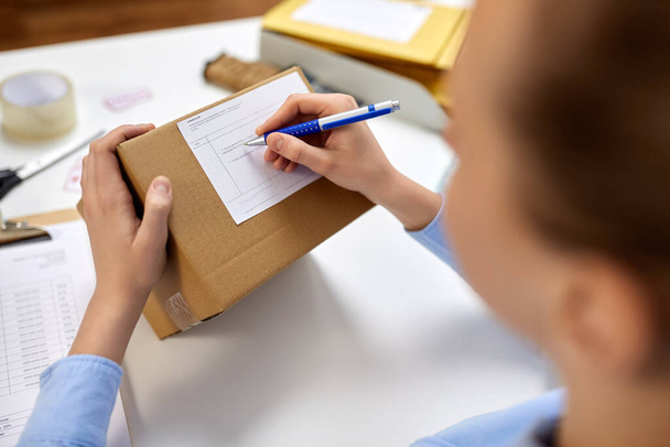 close up of woman filling postal form at office - Zdjęcie, obraz