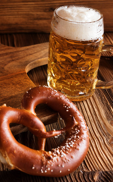 Bavarian bright draft beer with salt pretzel on rustic wooden table - Foto, Imagem