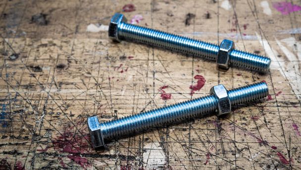 Bolts with metal hex nuts on  wooden workbench stained grunge te - Photo, Image