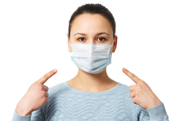 Studio portrait of young woman wearing a face mask, looking at camera, close up, isolated on gray background. Flu epidemic, dust allergy, protection against virus - Foto, Bild