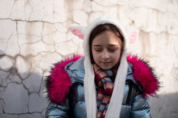 Милая маленькая девочка в капюшоне с ушами. девушка в шляпе кролика
 - Фото, изображение