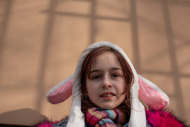 耳を持つフードのかわいい女の子。帽子のウサギの通りの女の子 - 写真・画像