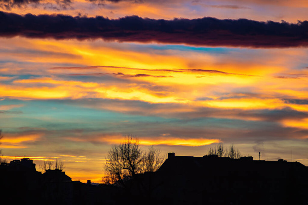 Céu colorido do por do sol sobre as casas da cidade
 - Foto, Imagem