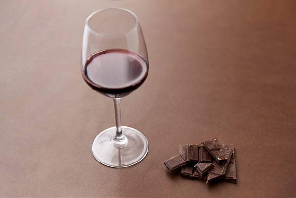 dark chocolate pieces and glass of red wine - Foto, afbeelding