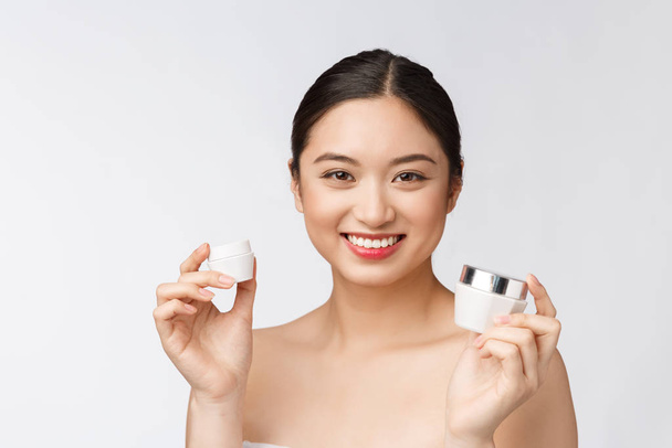 bela jovem mulher no branco isolado fundo segurando cosmético rosto creme asiático
 - Foto, Imagem