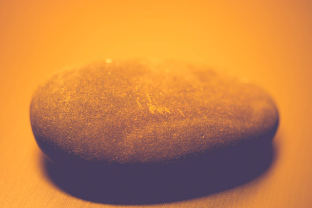 テーブルの上に大きな石が一つオレンジの光. - 写真・画像