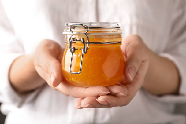 Woman with jar of orange jam, closeup - 写真・画像