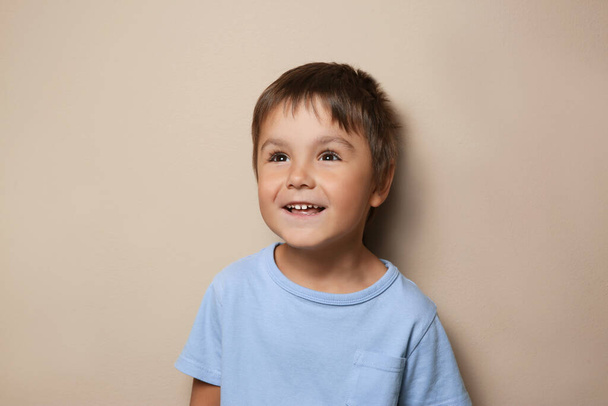 Portrait of cute little boy on beige background - Φωτογραφία, εικόνα