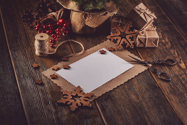 Jedle, dárkové krabice, nůžky, provaz a prázdný list papíru na dřevěném podkladu. Vánoční a novoroční dekorace. - Fotografie, Obrázek