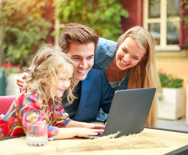 Young family together with their daughter looking at laptop  - Фото, изображение