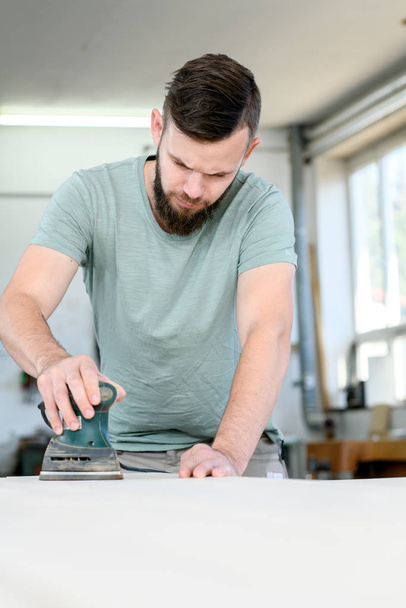 young worker with workpiece in a carpenter's workshop - Fotoğraf, Görsel