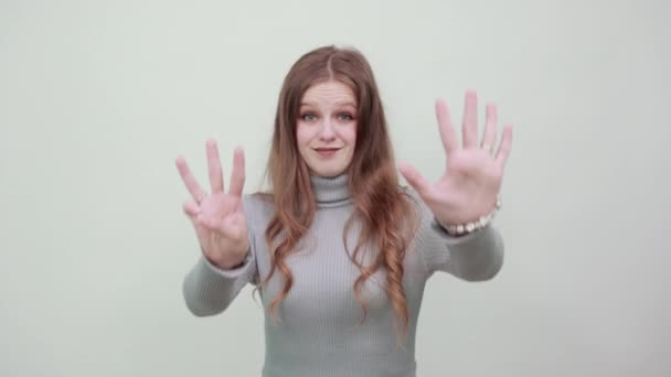 kobieta w szarym swetrze pokazuje numer dziewięć palcami - Materiał filmowy, wideo