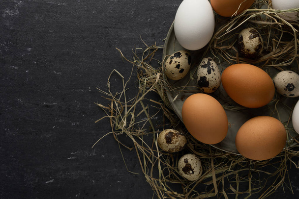 Quail eggs, brown chicken eggs, white chicken eggs on green plate and hay - Foto, Bild