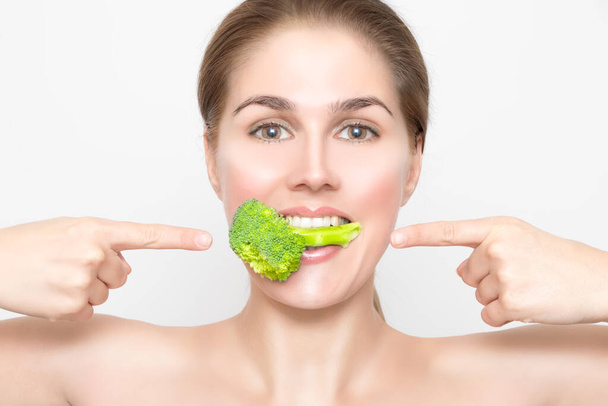 Woman's mouth with broccoli between big white teeth - Фото, изображение