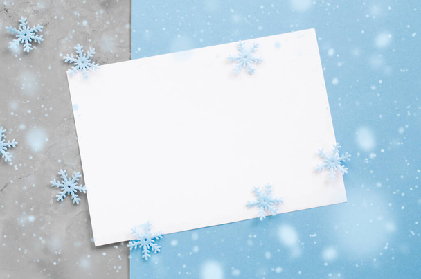 Minimalistic Christmas card mockup with decorative snowflakes in blue color. Empty postcard. Xmas background with snow effect. Top view with copy space. - Foto, Imagem