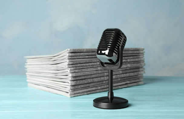 Newspapers and vintage microphone on light blue wooden table. Jo - Fotografie, Obrázek