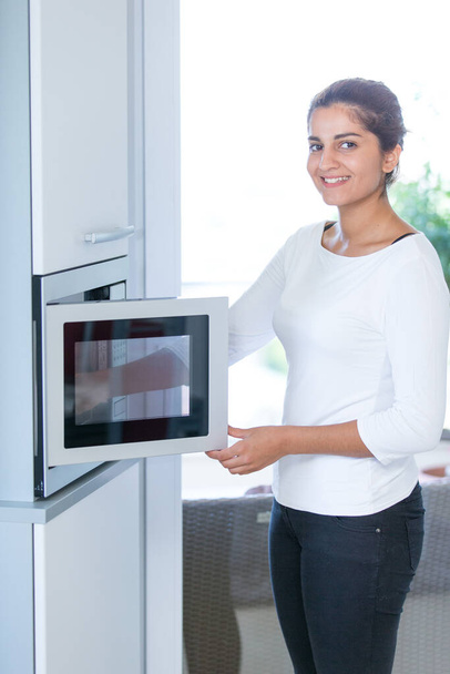 Woman using a microwave - Фото, изображение