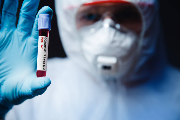 Coronavirus 2019-ncov δείγμα αίματος θετική λαβή τραυματιοφορέας σε λευκό Hazmat προστατευτικό. Ιός επιδημίας αντίληψης - Φωτογραφία, εικόνα