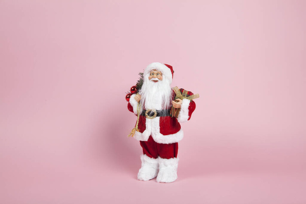 a santa claus figurine plush on a pink background. Color harmony. Minimal still life color photography - Photo, Image