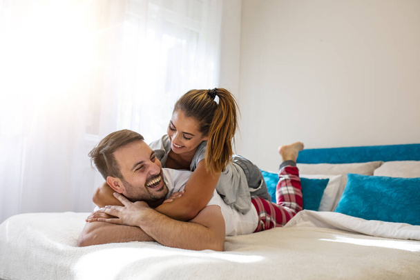 Couple in love in bed at home. Couple in love wearing pajamas cuddling while lying in bed. Young happy couple in love lying on bed and enjoying each other. Couple at morning time. Close up. - Φωτογραφία, εικόνα