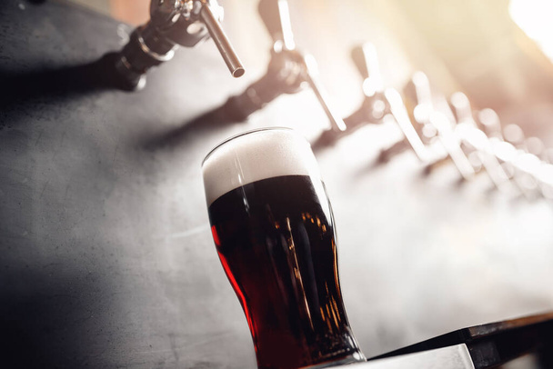 Dark Draft bière froide verser dans le verre de la grue dans le pub
 - Photo, image