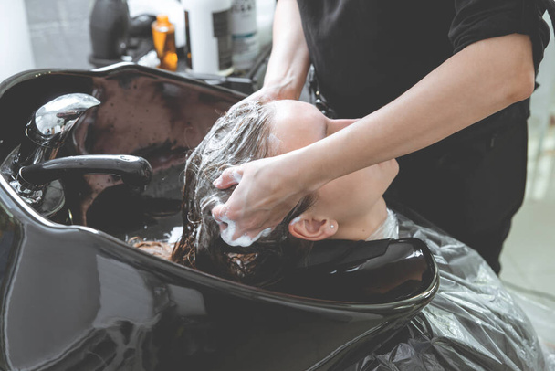 hair stylist washing hair of yong blonde girl in hair salon before haircut - Photo, Image