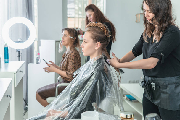 Hairdresser brushing long blonde hair with brush in beauty salon - Photo, Image