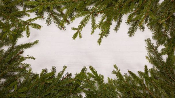 White wooden background with frame from fir branches. New Year and Christmas - 写真・画像