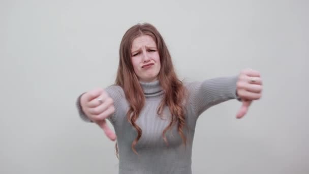 γυναίκα με γκρι πουλόβερ ένα εξοργισμένο κορίτσι επιστρέφει αντίχειρες προς τα κάτω επιδεικνύει θυμό - Πλάνα, βίντεο