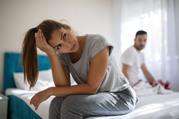 Couple having arguments and sexual problems in bed. Portrait of unhappy young heterosexual couple in bedroom. Picture showing young woman and her man having problem in bedroom - Zdjęcie, obraz