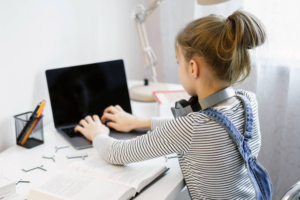 Genç kız ödevini evde yapıyor ve dizüstü bilgisayar kullanıyor. - Fotoğraf, Görsel