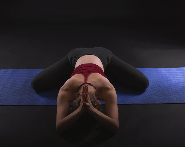 Mujer joven practicando Yoga Mudra, Yoga Mudrasana, Yoga Mudrasan, Yoga Mudra Asana sobre fondo negro
. - Foto, imagen