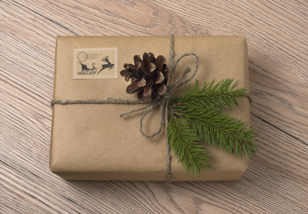 Christmas or New Year gift boxes wrapped in kraft paper with fir branch on wooden background. - Photo, Image