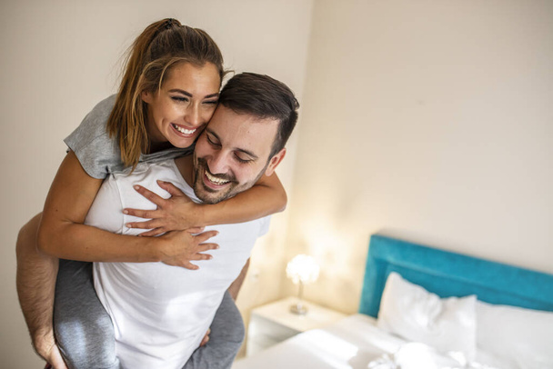 Head shot happy millennial young man and woman hugging embracing indoors. Portrait close up smiling husband and wife piggyback ride. Dating and romantic relationship concept - Photo, image