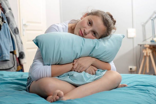 pensive teenager girl with a pillow sitting on bed - Фото, зображення