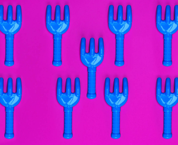 lots of blue plastic baby rakes on pink background - Photo, Image