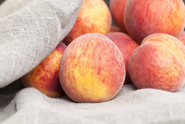 熟した大きな桃の束果物はリネンのテーブルクロスに入っています - 写真・画像