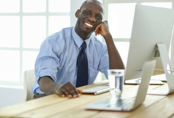 African american businessman on headset working on his laptop - Foto, Imagen