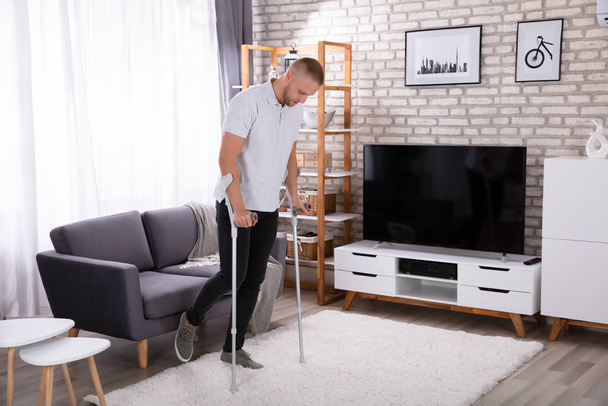 Disabled Young Man Using Crutches To Walk On Carpet - Photo, image
