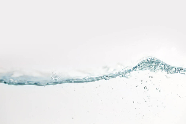 Fermer les éclaboussures d'eau avec des bulles d'air. Aqua de surface frais et propre coulant dans les vagues et l'eau propre sur fond blanc isolé. Image publicitaire avec espace libre pour votre travail   - Photo, image