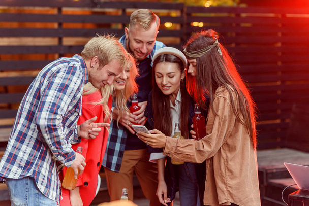 Group of happy young friends enjoying weekend at the party using smartphone sharing selfie photo on social networks. - Fotó, kép