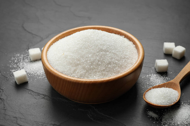 Гранулированный сахар в миске на тёмном столе
 - Фото, изображение