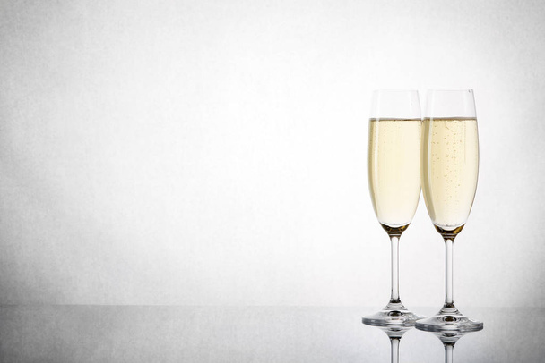 Two wineglasses with champagne isolated on a grunge gray background with reflection. Copy space - Valokuva, kuva