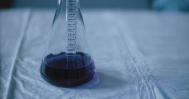 Scientist taking out a purple liquid from a conical flask to test chemicals for reactions in a lab. Close up, handheld, slow motion, shot with BMPCC 4K. Concept: science, chemistry, biotechnology.    - Кадры, видео