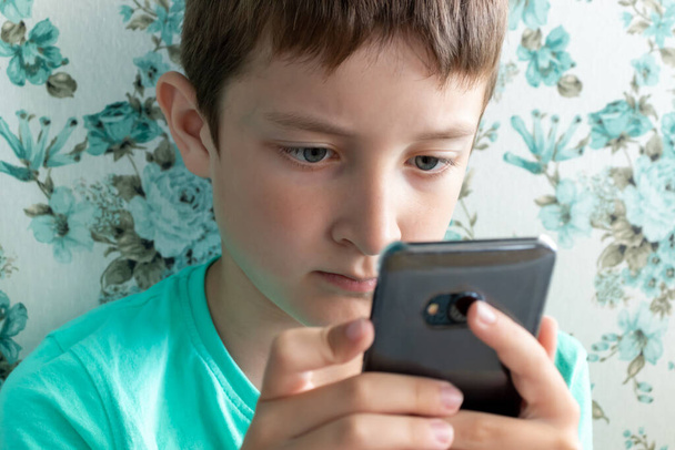 Children, digital technology and internet concept, preteen boy child playing games or surfing internet on digital smartphone while sitting in a cafe - Foto, imagen