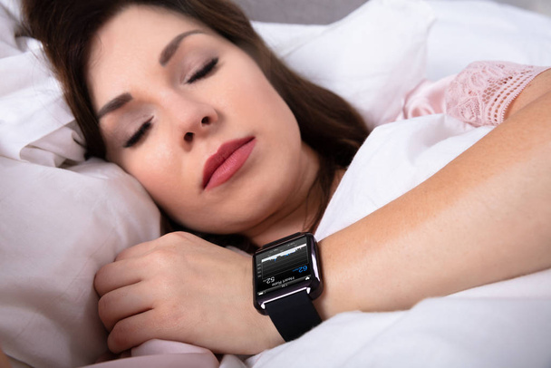 Beautiful Woman Sleeping On Bed With Smartwatch Showing Heartbeat Rate - Photo, Image