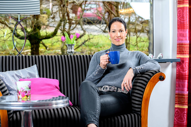 young dark haired woman at home with cup of coffeee relaxing - Foto, Bild