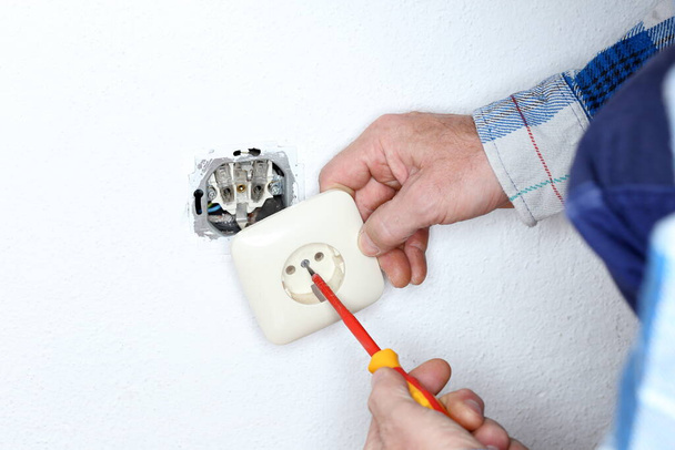 electrician worker is mounting a wall socket - Foto, imagen